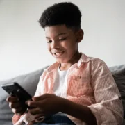 A boy sits on the sofa looking at his phone
